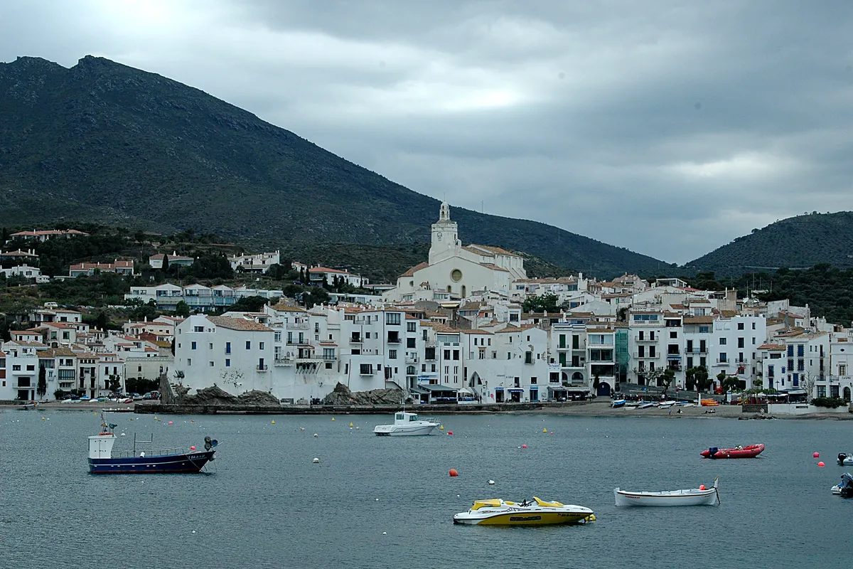 Cadaqués vist des del mar, amb les cases blanques al voltant de la badia i l’església de Santa Maria al capdamunt