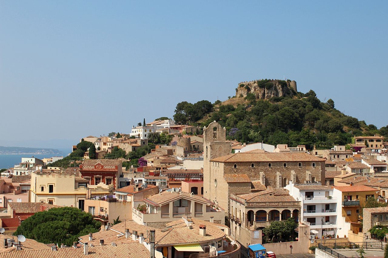 Begur, amb el castell en ruïnes dalt del turó, l'església de pedra, teulades de terracota i el mar a l'esquerra