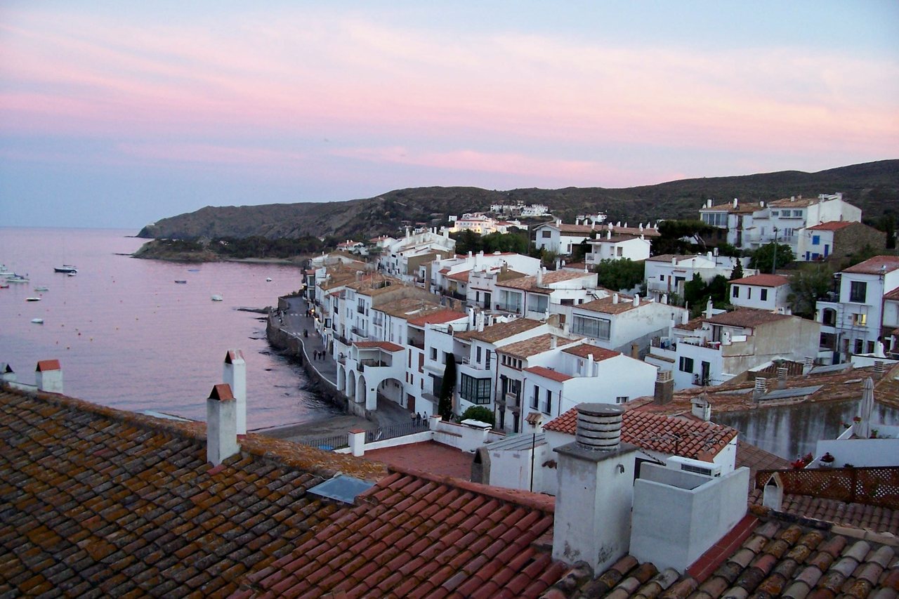 Cadaqués al capvespre, amb les cases blanques al voltant de la badia i els terrats en primer terme