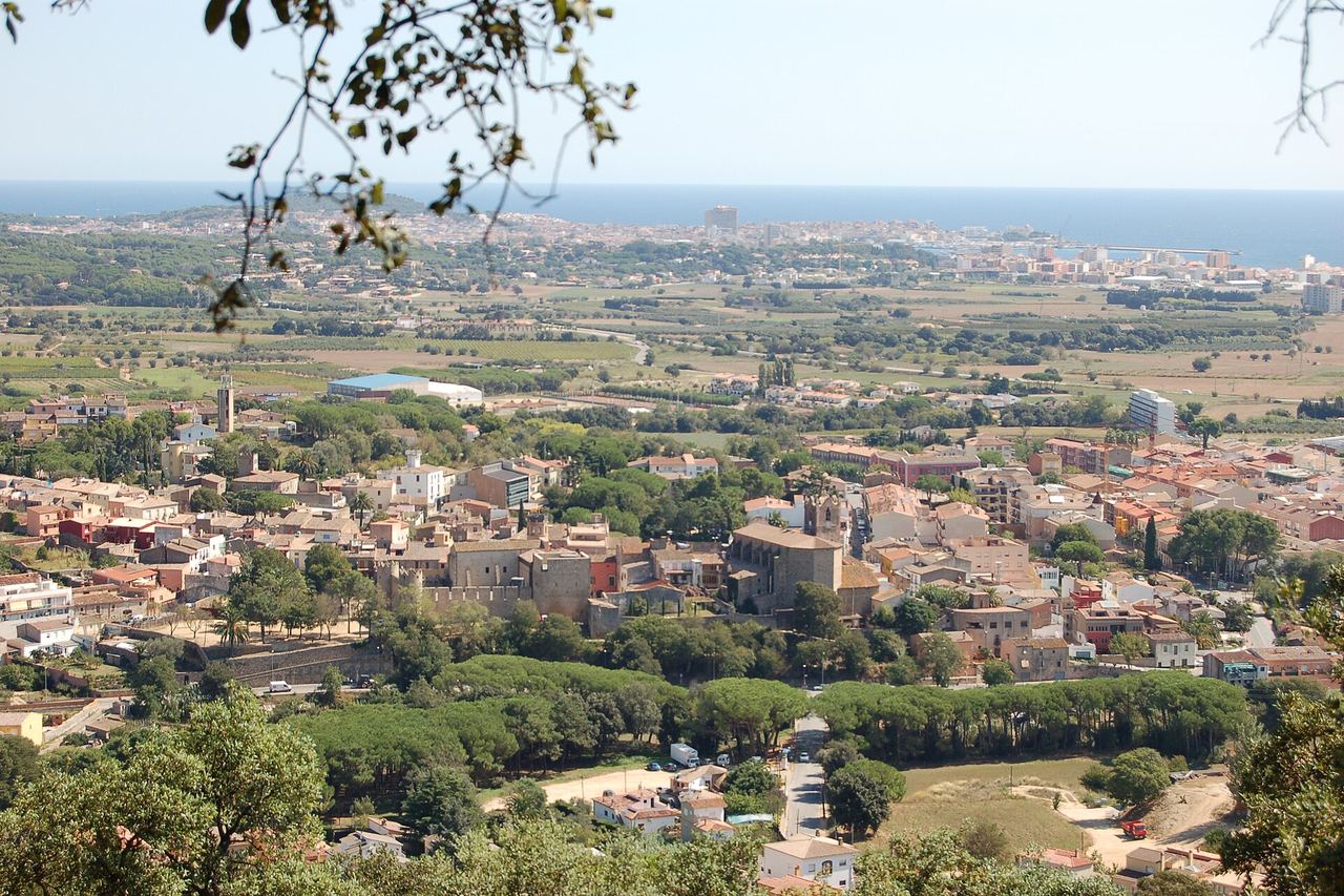 Calonge i Sant Antoni des d'un turó: la vila amb el castell i l'església, una pineda, camps i, al fons, la costa i el mar