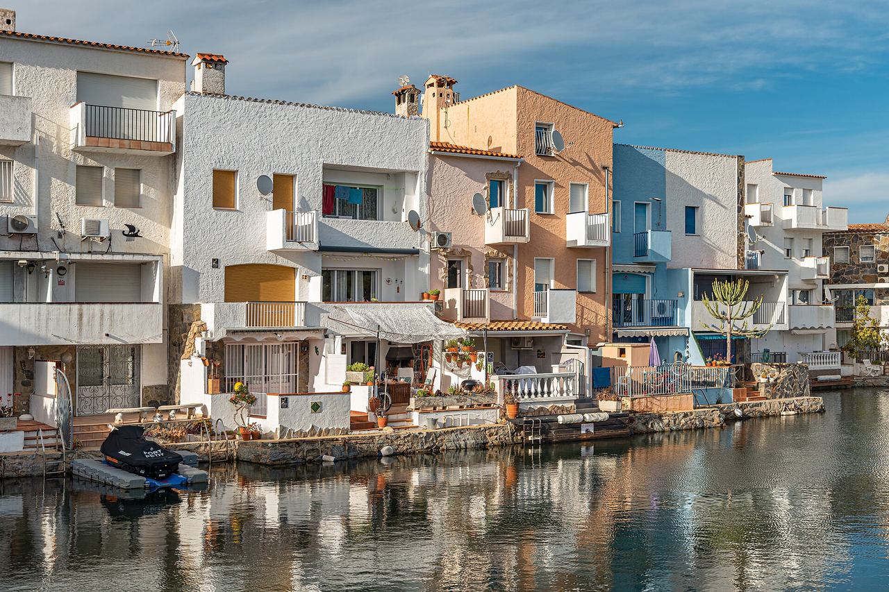 Casas de Empuriabrava a la orilla de un canal, con una barca amarrada delante