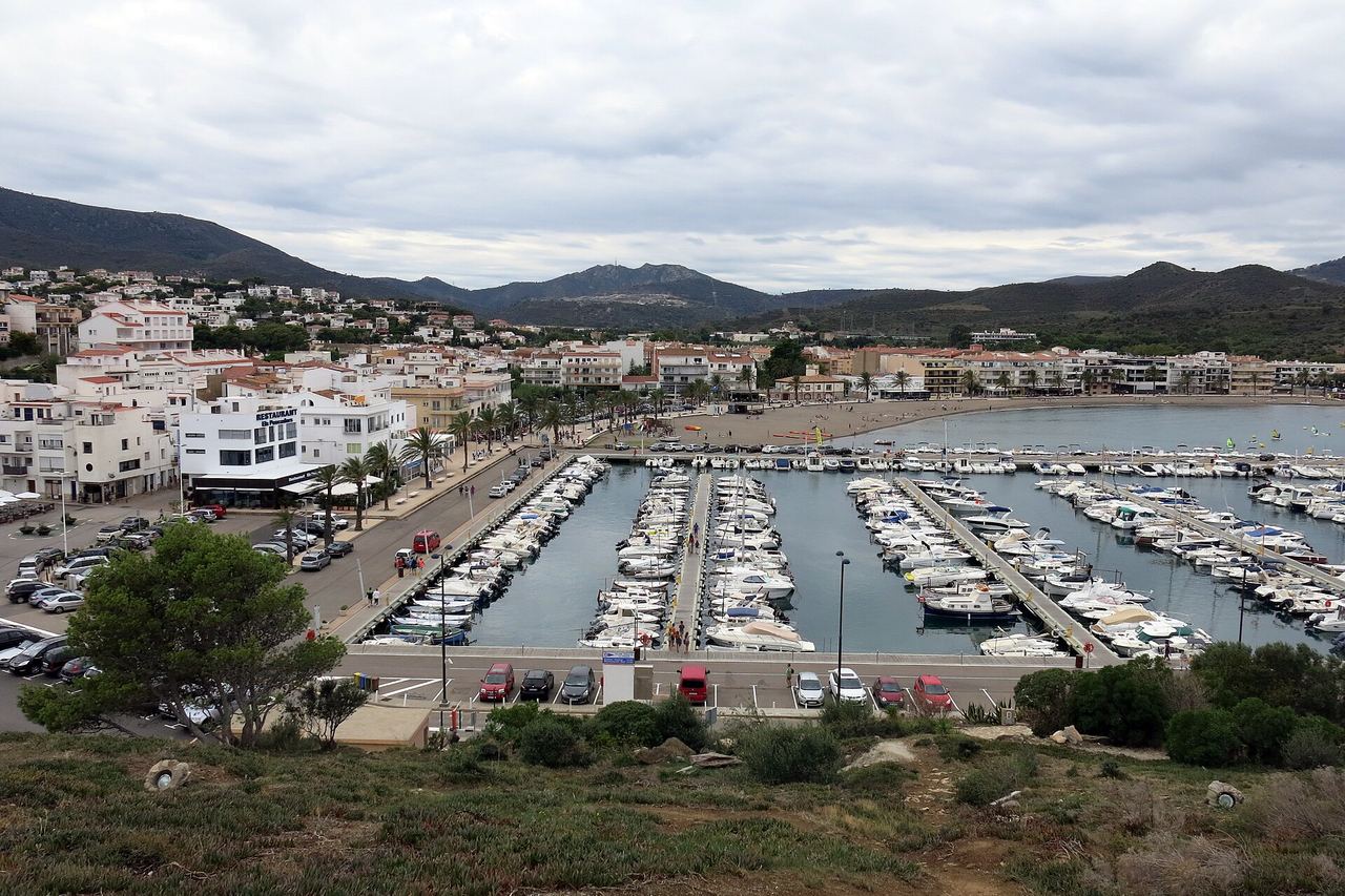 El puerto de Llançà lleno de barcas, con las casas blancas del pueblo y las montañas detrás