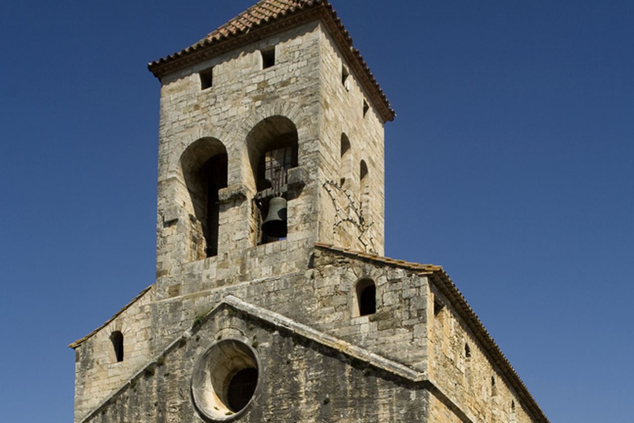 L'església de Sant Vicenç de Maià de Montcal: campanar de pedra amb una campana, ull de bou a la façana i cel blau
