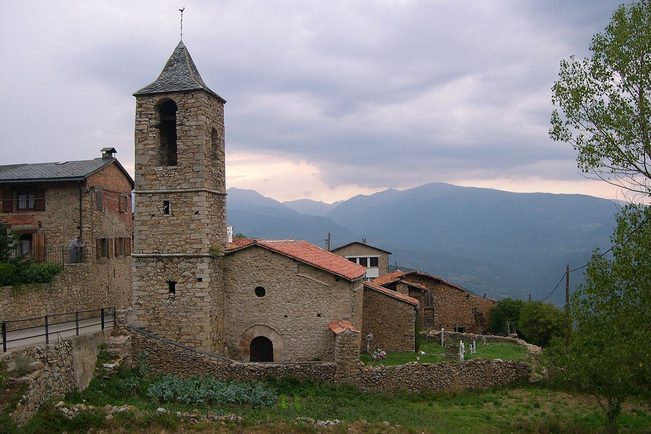 Sant Climent d'Estana, a Montellà i Martinet: església de pedra amb campanar, el cementiri al costat i muntanyes al fons