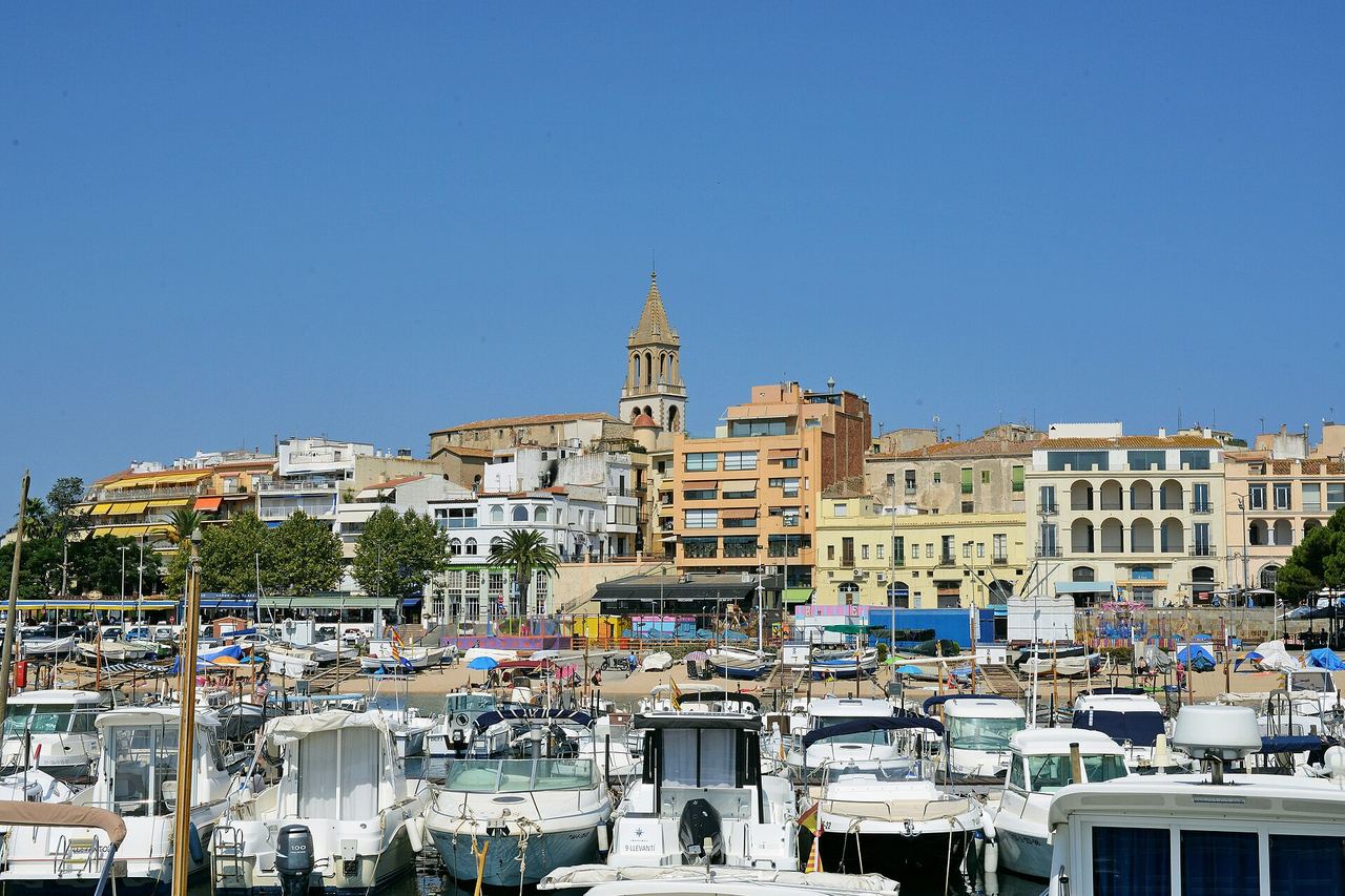El puerto de Palamós lleno de barcas, con el casco antiguo y el campanario de la iglesia detrás