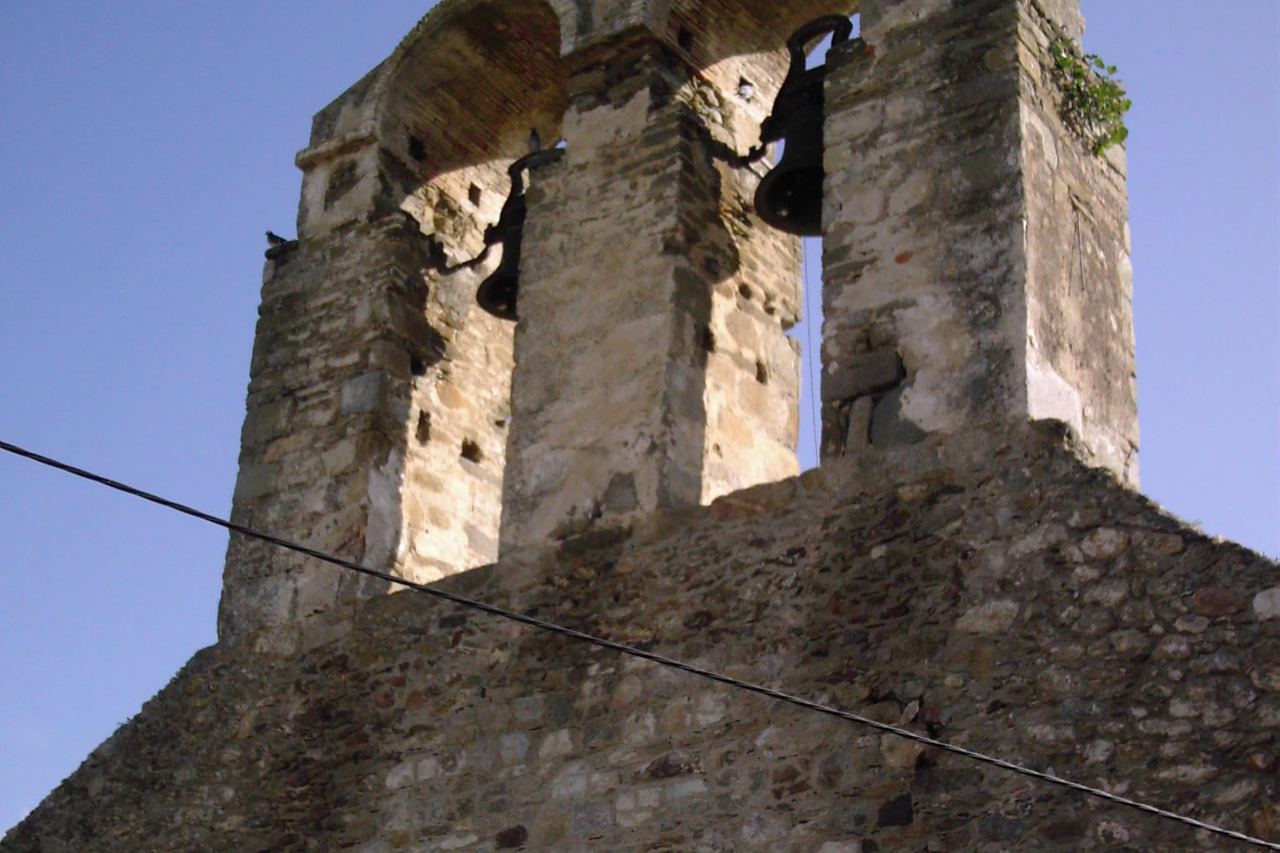 El campanar d'espadanya de l'església de Sant Joan de Palau-saverdera, de pedra i amb dues campanes, contra el cel blau