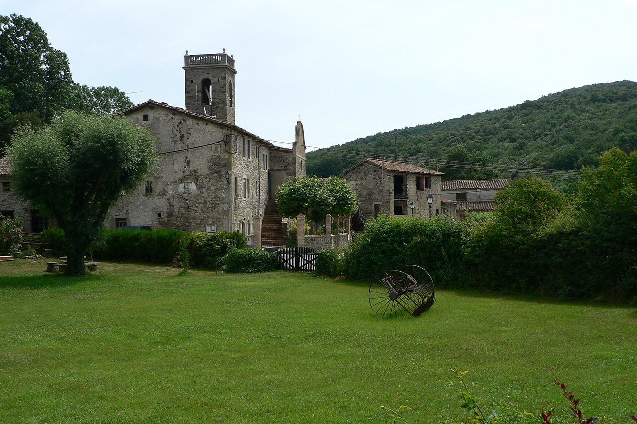 El Torn, a Sant Ferriol: l'església amb el campanar, cases de pedra i un prat amb una antiga eina agrícola