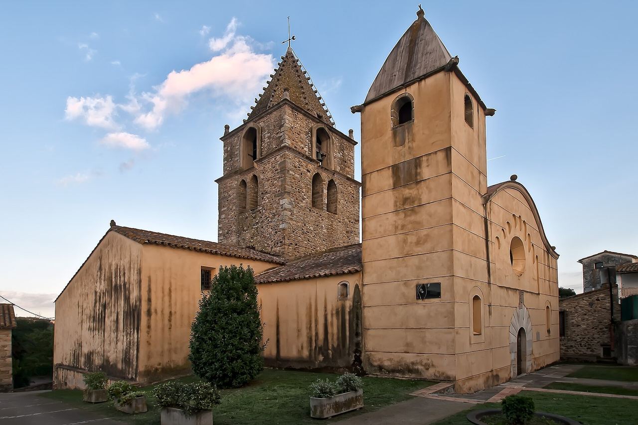 L'antiga església de Sant Gregori, amb un campanar de pedra, una torre arrebossada i gespa amb jardineres al davant