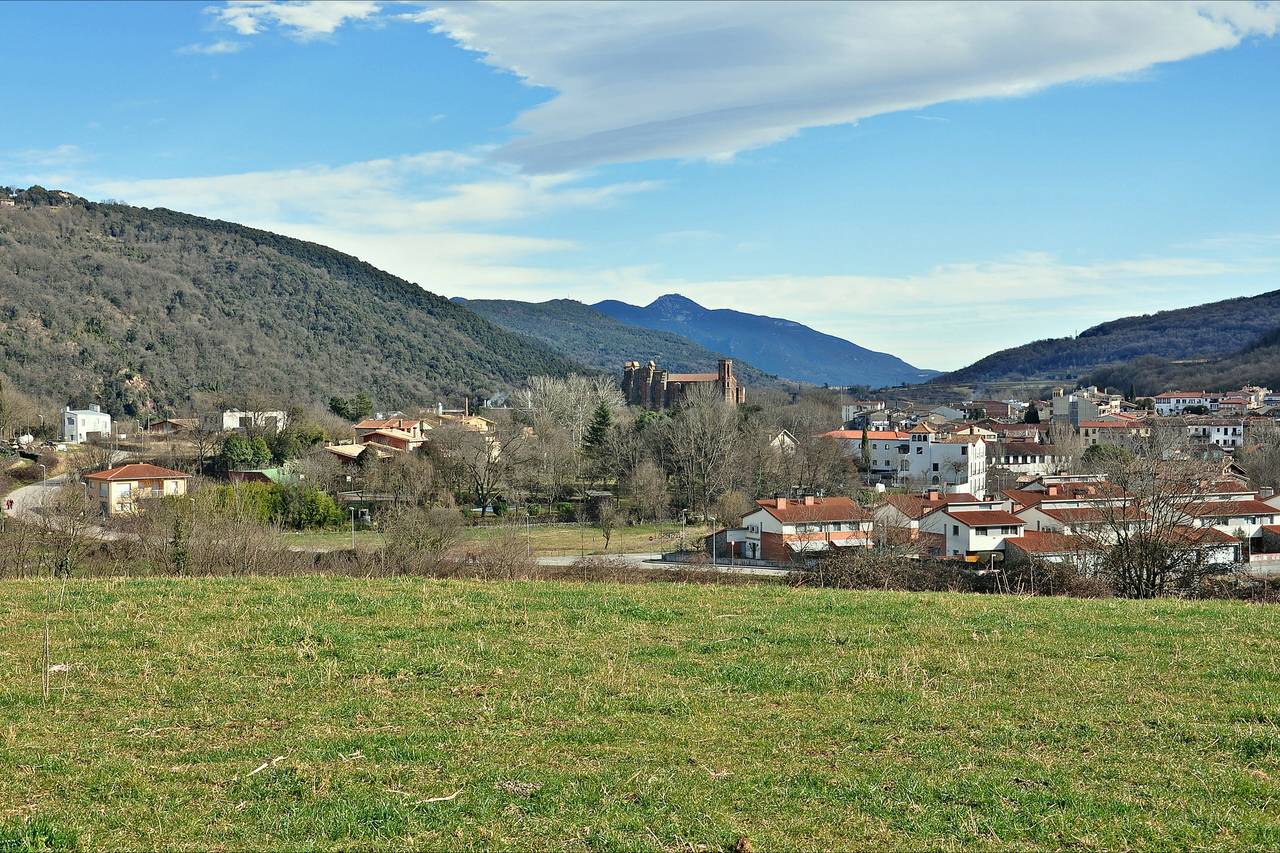 Vista de Sant Joan les Fonts, amb el monestir al mig del poble i les muntanyes de la Garrotxa al fons