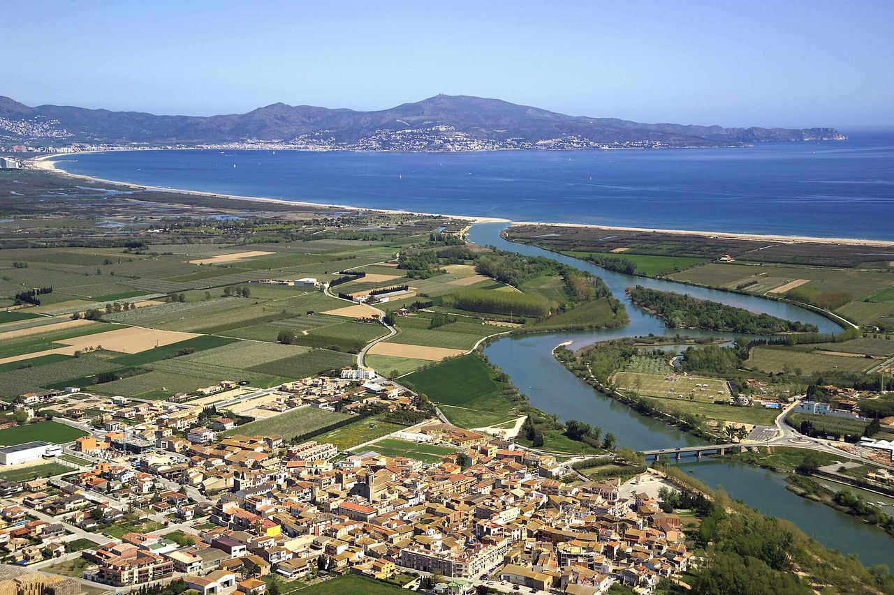 Vista aèria de Sant Pere Pescador, amb les cases del poble, el riu que serpenteja entre camps i el golf de Roses al fons
