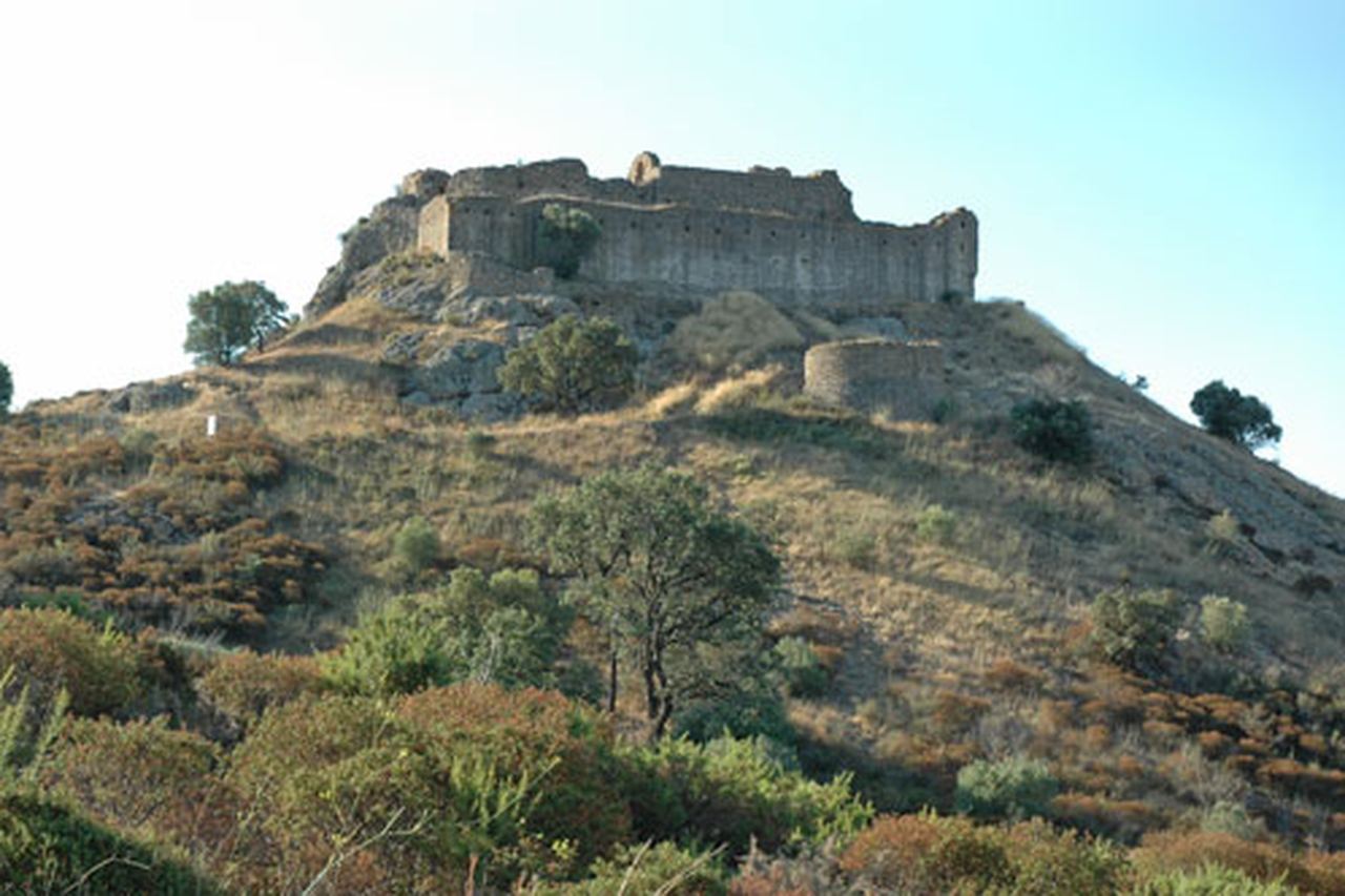 Les muralles del castell de Quermançó, dalt d'un turó rocós cobert de matolls, al terme de Vilajuïga